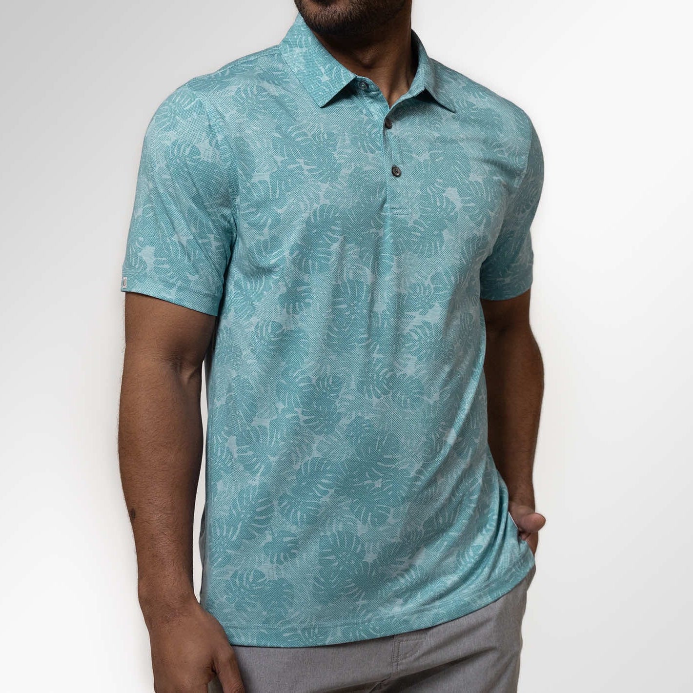 Man wearing a teal patterned polo shirt against a white background
