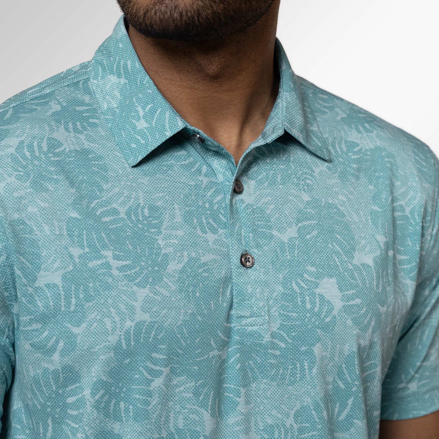 Teal patterned polo shirt worn by a person on a plain background