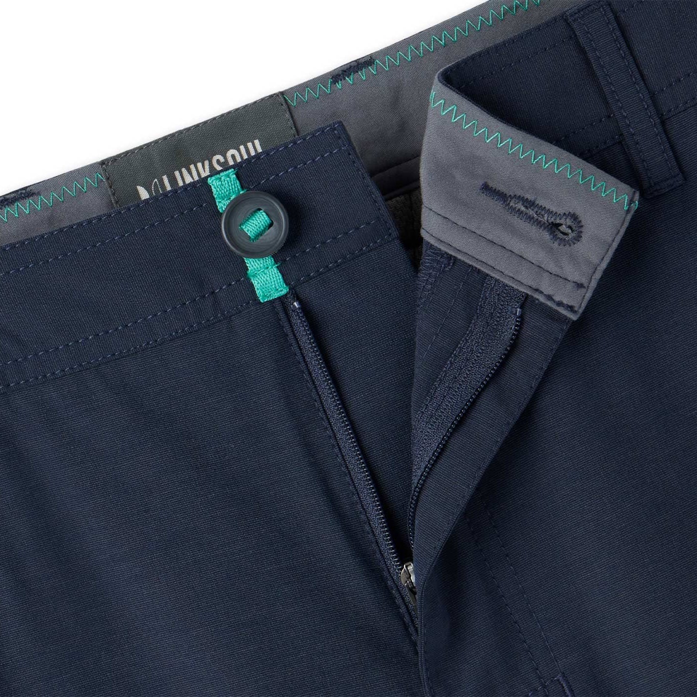 Close-up of navy blue pants with a button and zipper detail, featuring a brand logo.