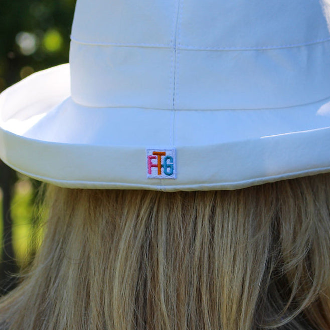 Person wearing a white bucket hat with a logo outdoors