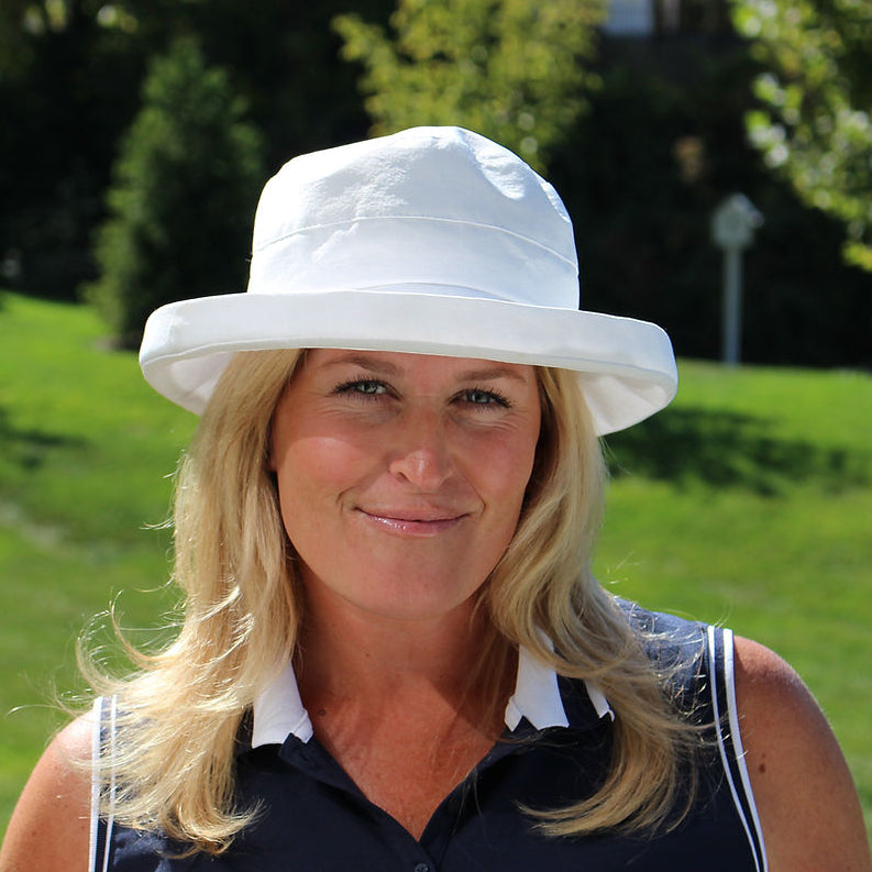 Woman wearing a white hat in a grassy outdoor setting